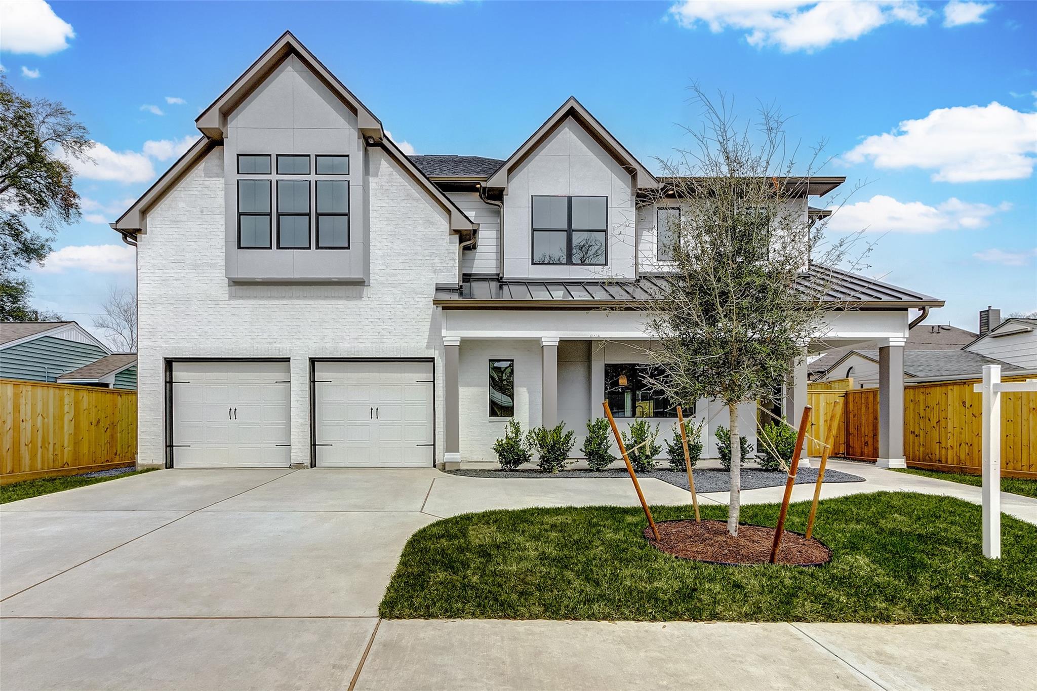 Front elevation of the completed SLC custom home at 6522 Westview Drive in Houston, with white brick, twin gables and black windows